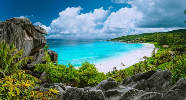 Picturesque panoramic shot of Grand Anse, La Digue island, Seychelles. Огромное гранитное каменное образование, яркий белый песок тропический пляж с бирюзовой голубой кристально чистой водой и облаками — стоковое фото