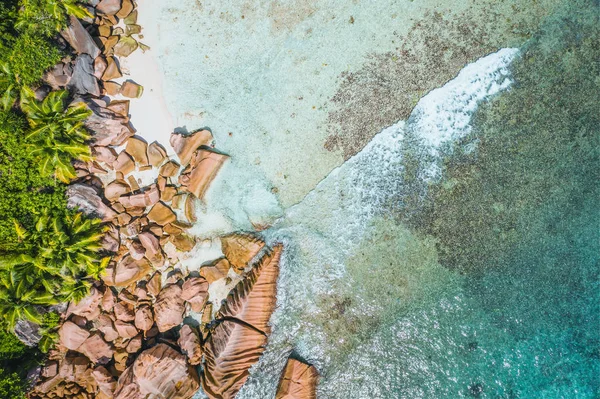Luftaufnahme von Meereswellen, die auf Granitfelsen am tropischen Strand in La Digue auf den Seychellen treffen — Stockfoto