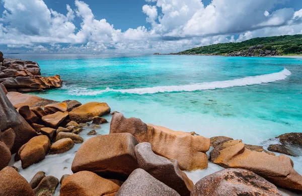 Катящаяся волна и потрясающие гранитные образования на красивом тропическом острове с белыми облаками Ла-Диг, Сейшелы — стоковое фото