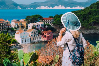 Sevimli renkli küçük Assos köyünde güneş şapkalı turist sarışın kadın. Kefalonia, Yunanistan