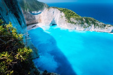 Önünde yeşil bitki örtüsü olan Navagio sahilinin geniş bir manzarası var. Yunanistan 'ın Zakinthos adasının ünlü manzarası