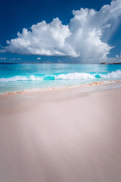 Beautiful white ocean wave rolling towards tropical sandy beach. Fluffy clouds above blue sea. Grand Anse, Seychelles — Stock Photo, Image