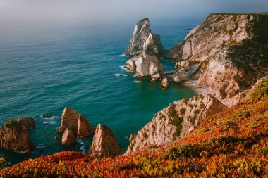 Praia Da Ursa Sahili, Sintra, Portekiz 'de altın ateş günbatımında gerçeküstü ve tuhaf yüksek kayalar. Portekiz 'de Cabo Da Roca yakınlarında Atlantik kıyısında.