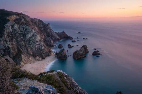 해질 녘, 숨어 있던 초현실적 인 프라 이아 다 우르 사 해변의 일몰 광경. 카보 다 로카 (Cabo da Roca) 배경에 라이트 하우스가 있다. 대서양 연안, 포르투갈, 유럽 — 스톡 사진