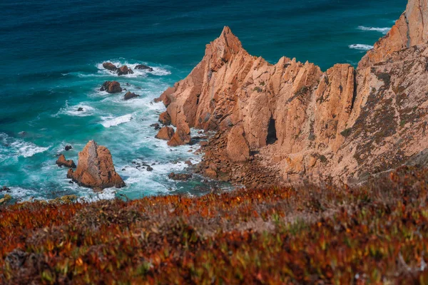 लोकप्रिय पर्यटन काबो दा रोका लाइटहाउस, पुर्तगाल के पास अटलांटिक महासागर तट पर सुंदर नारंगी रंगीन चट्टानों के साथ Praia do Ursa समुद्र तट — स्टॉक फ़ोटो, इमेज