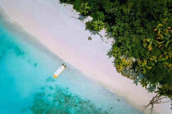 Vista aérea de cima para baixo da exótica praia de areia tropical com lagoa azul, palmeiras e barco linely atracado — Fotografia de Stock