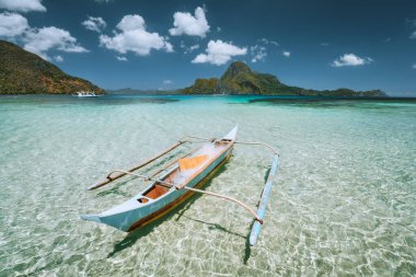 Palawan, Filipinler. Cadlao Adası 'nın önündeki geleneksel küçük balıkçı teknesi alçak gelgit sırasında kristal berraklığında sığ sularda
