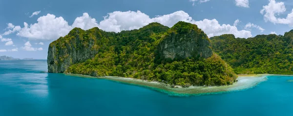 Aerial panoramic drone view of uninhabited tropical island with towering mountains and rainforest jungle surrounded by blue ocean — Stock Photo, Image