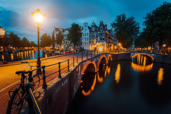 Vista notturna della città di Amsterdam. Ponte illuminato sul canale di Herengracht. Tipiche case olandesi a luci orarie, Olanda, Paesi Bassi — Foto Stock