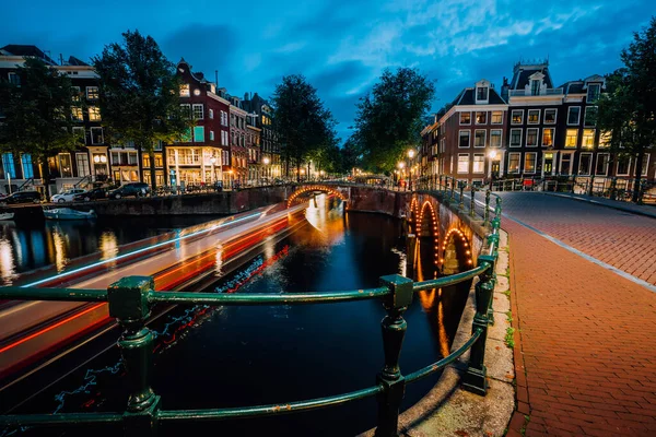 Tarde en la ciudad de Ámsterdam, senderos ligeros y reflejos sobre el agua en los canales Leidsegracht y Keizersgracht. Disparo de larga exposición. Viaje a la ciudad concepto de visita — Foto de Stock