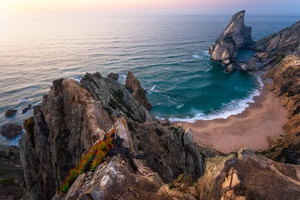 Praia da Ursa Beach shora. Skalnaté popředí se žlutými květy v zapadajícím slunci. Surrealistická scenérie Sintry, Portugalsko. Pobřežní krajina Atlantského oceánu — Stock fotografie