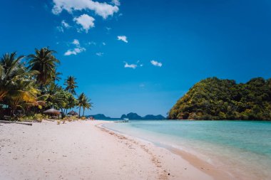 El Nido, Palawan, Filipinler. Sığ göl, palmiye ağaçlı kumlu sahil. Seyahat ve tatil kavramı