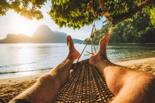 Pés de homem adulto relaxando em uma rede na praia durante as férias de verão — Fotografia de Stock