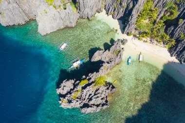 El Nido, Palawan, Filipinler, göldeki teknelerin havadan görünüşü ve Gizli Göl Sahili 'ndeki kayalık dağlar.