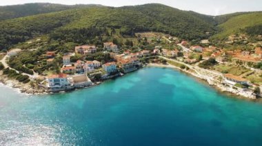 Kıyı köyü Fiskardo 'nun evleri ve turkuaz körfez suyuyla hava manzarası.