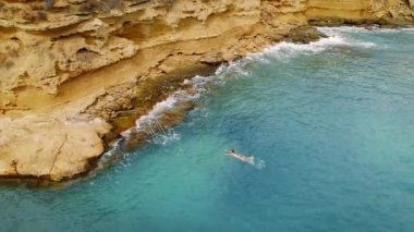 Yazın açık mavi sularda Pessada sahilinin kayalık uçurumlarında yüzen kadın Kefalonia.