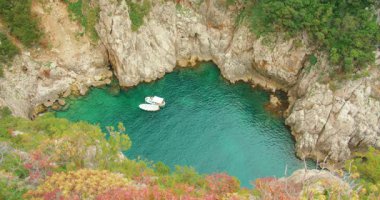 Capri 'de kayalıklarla çevrili beyaz kayıklar canlı yeşil körfezde yüzer..