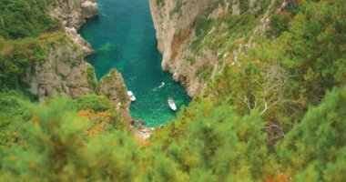 Capri 'deki dar bir kıyı kayalık koyunda turkuaz suya demirlenmiş tekneler..