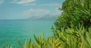 Hırvatistan 'da yaz aylarında turkuaz deniz ve uzak dağların manzarası yeşil santrallerle çevrili.