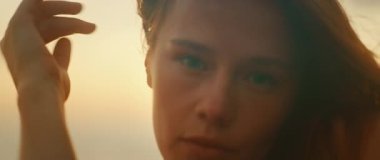 Gün batımında günbatımında kadın yüzü ve elleri yavaş çekimde dans ederken.