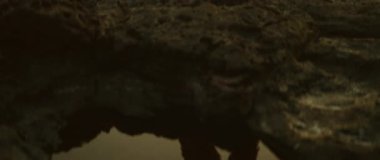 Akşam ışığı altındaki volkanik kayalıklarda dans gösterisi sırasında suda yansıyan kadın..