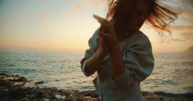 Tenerife İspanya 'da günbatımında okyanus kenarında çağdaş dans eden bir kadın..