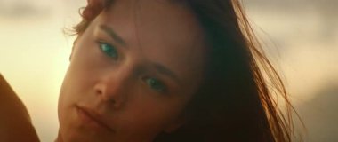 Okyanus kıyısında gün batımında dans gösterisi sırasında yoğun bakışlarla kadının yüzüne yakın çekim..