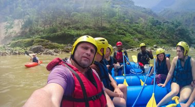 Bhote Koshi river, Nepal - April 09, 2018: The people sitting at boat at rafting on the Bhote Koshi in Nepal. The river has class 4-5 rapids. clipart