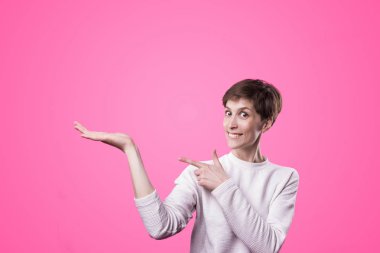 Heyecanlı kız pembe arka plan kopya alanı ile gösteren işaret. Genç güzel mutlu gülümseyerek ve kadın gülüyor