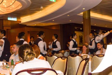 Cape Canaveral, Amerika Birleşik Devletleri - 29 Nisan 2018: Dans ve şarkı garsonlar ve lüks yolcu gemisi Oasis Royal Caribbean tarafından denizlerin yemekler ile Grande restoran ve tablolar aşçılar.