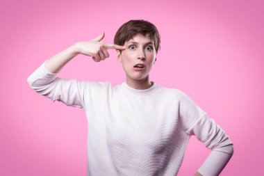 Avrupa kadın duygusal şakağına silah, yeşil duvardan şaşkın gibi için parmak koyarak görüntüsünü.