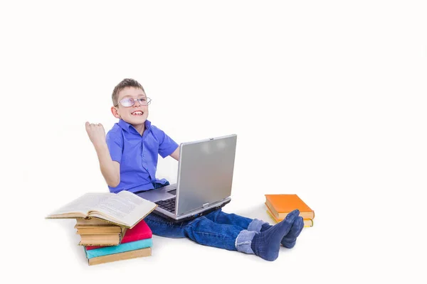 Retrato de colegial lindo sentado con libros y mecanografía en el teclado del ordenador portátil — Foto de Stock