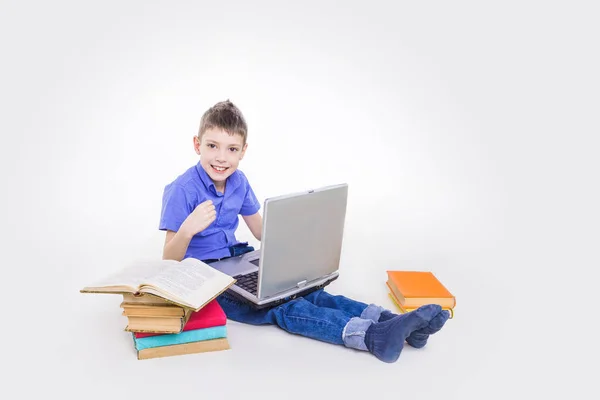 Retrato de colegial lindo sentado con libros y mecanografía en el teclado del ordenador portátil — Foto de Stock