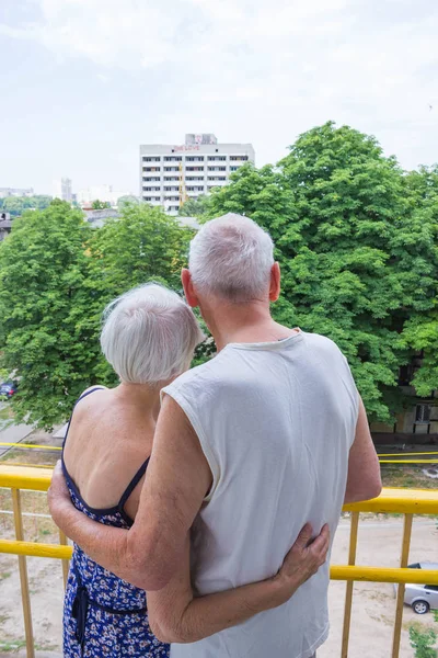 Старшая пара стоит oustide на балконе дома и смотрит в сторону — стоковое фото