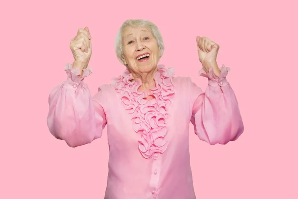 Улыбающаяся счастливая зрелая женщина в розовой блузке. На розовом фоне — стоковое фото