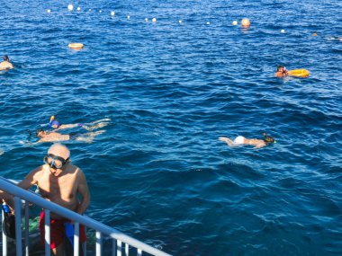 İnsanlar, Mısır 'ın Sharm El Sheikh kentindeki kızıl denizde mercan resifinin üzerindeki mavi sularda şnorkelle yüzüyorlar.