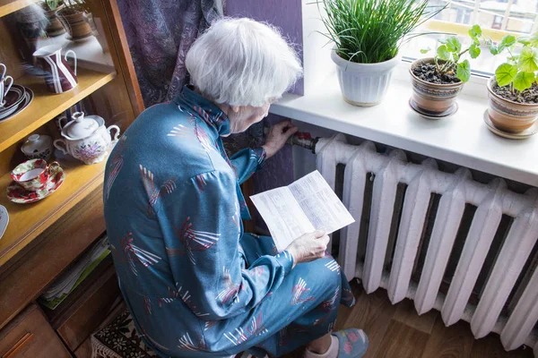 Femme tenant de l'argent devant le radiateur de chauffage. Paiement pour le chauffage en hiver. Concentration sélective . — Photo