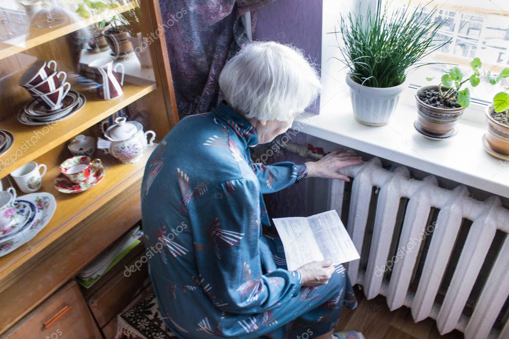 Woman holding cash in front of heating radiator. Payment for heating in winter. Selective focus.