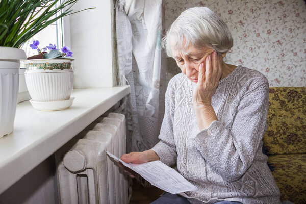 Woman holding cash in front of heating radiator. Payment for heating in winter. Selective focus.
