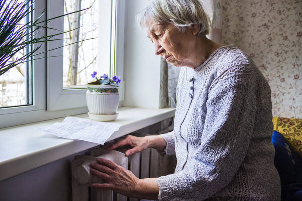 Woman holding cash in front of heating radiator. Payment for heating in winter. Selective focus.