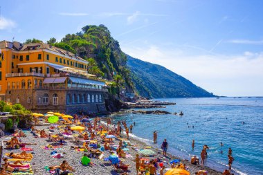 Camogli, İtalya - 15 Eylül 2019: Güneşli yaz gününde insanlar Camogli plajında dinleniyor