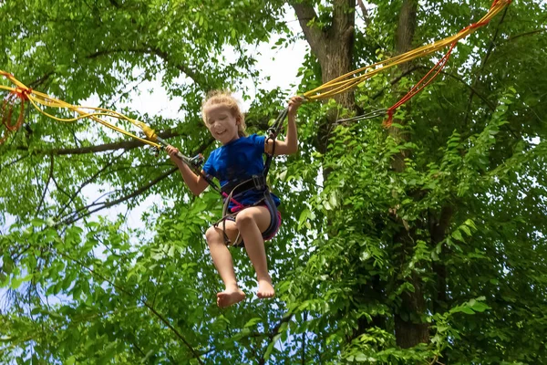 Usmívající Šťastná Dívka Skákání Bungee Trampolíně Parku Proti Zeleným Stromům — Stock fotografie