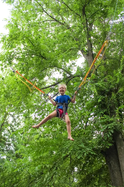 Menina Feliz Sorrindo Pulando Com Bungee Trampolim Parque Contra Árvores — Fotografia de Stock