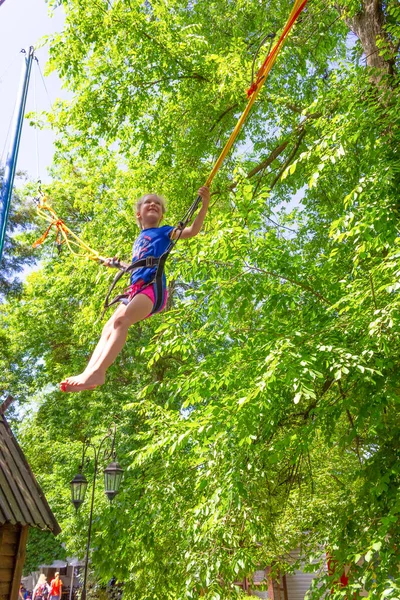 Usmívající Šťastná Dívka Skákání Bungee Trampolíně Parku Proti Zeleným Stromům — Stock fotografie