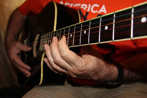 The fretboard of an old acoustic guitar and fingers on strings. Selective focus