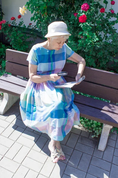 引退した女性は屋外の公園で新聞を読んで — ストック写真