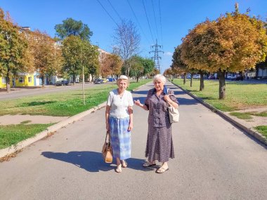 Şehir caddesinde ilerleyen iki son sınıf öğrencisi bayan. Yazın olgun kadınların manzarası