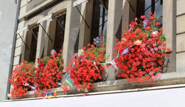 Cenevre, İsviçre 'deki eski evde çiçek ve bayraklı klasik pencere.