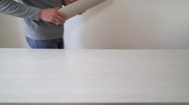 Tamirci yeni duvar kağıdı rulo tablo kapalı üzerinde işaretleme için hazırlanıyor