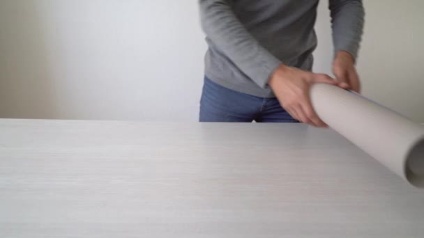 Майстер готує новий рулон шпалер і вимірює за допомогою мірної стрічки на столі в приміщенні — стокове відео